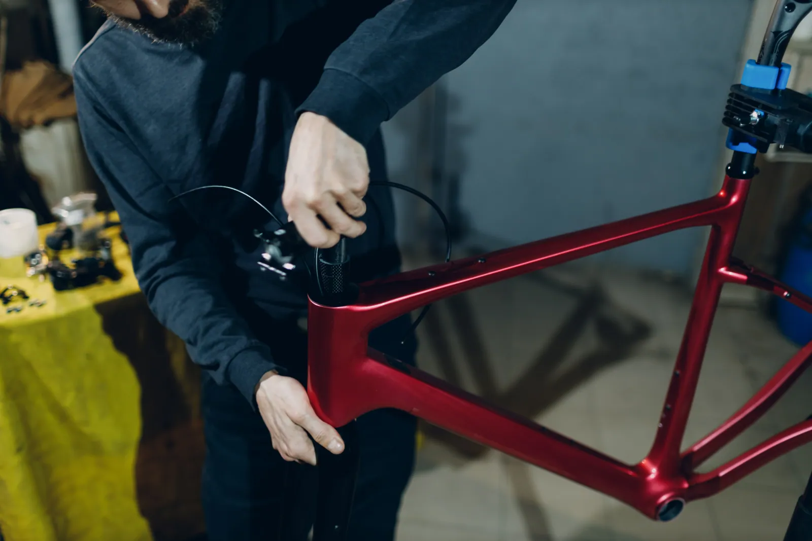 Bicycle frame on a workshop stand with cockpit components arranged alongside, the visual signature for a frame-and-cockpit supplier